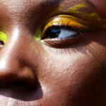 Close up on woman's eyes with fluorescent yellow graphic eyeliner