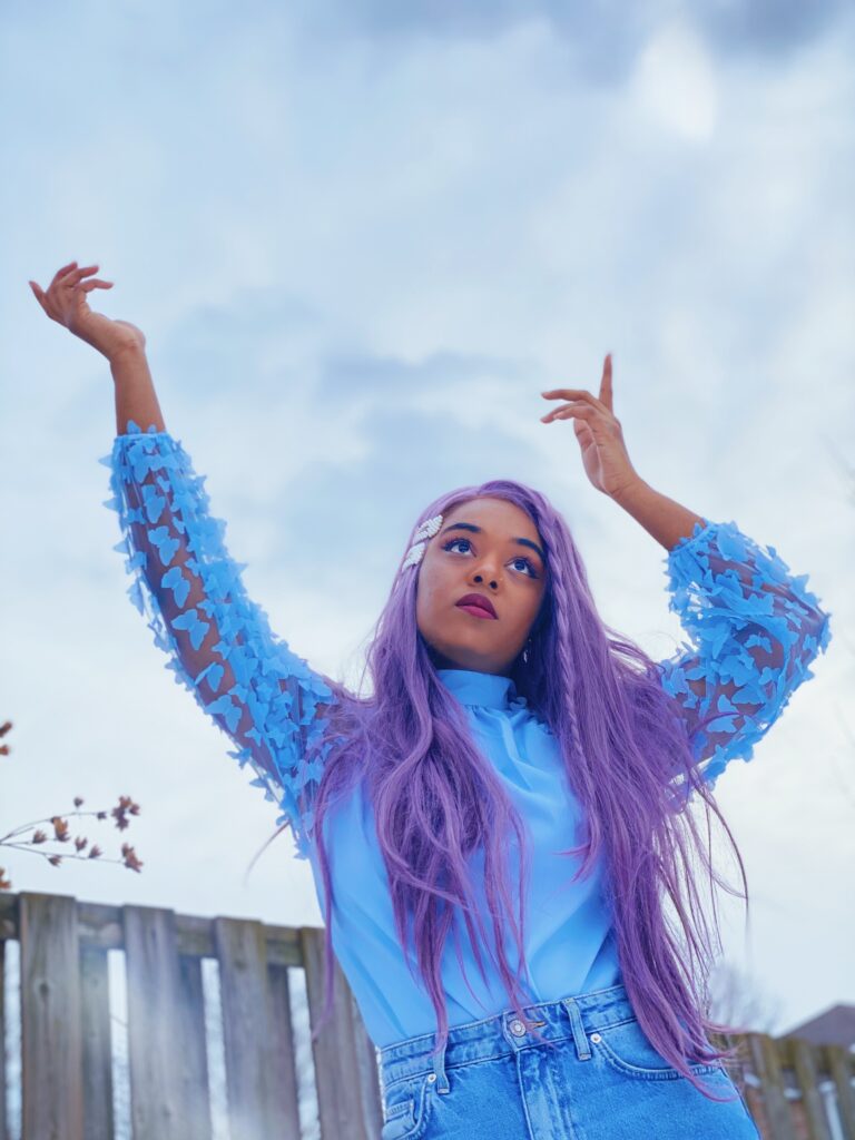 Maya is wearing a blue blouse from SHEIN, hair clips from wowyesh, mom jeans from H&M and purple wig from FOXWIGS.