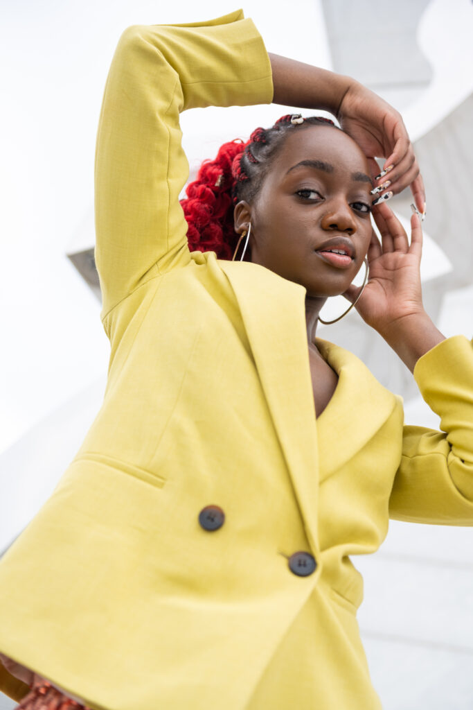 Close-up of a black woman wearing a lime blazer, framing her face with her hands