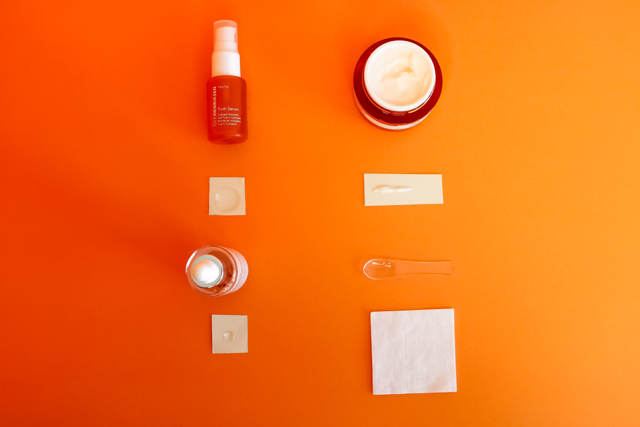 Tonal flat lay photograph of 3 skincare products and an orange against a solid orange coloured background.